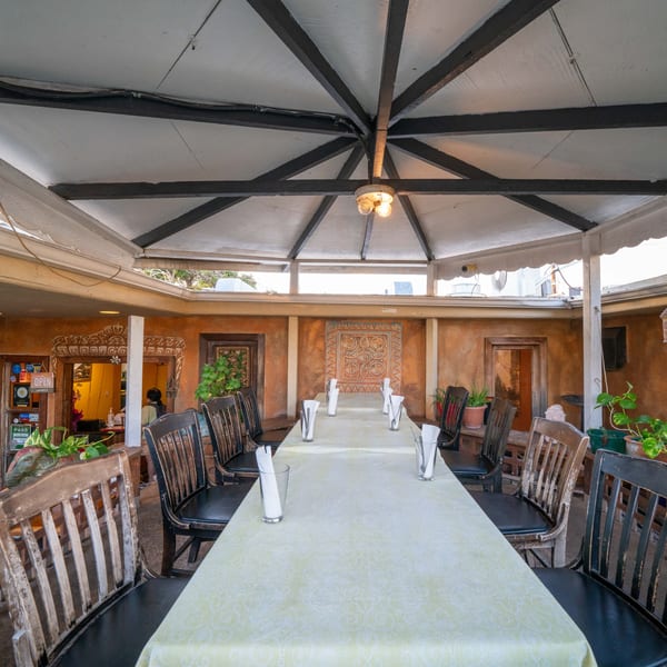 Long dining table set with glasses and napkins under a covered patio at Himalayan Kitchen Hawaii.